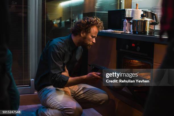 man checking on food in oven - kitchen oven stock-fotos und bilder