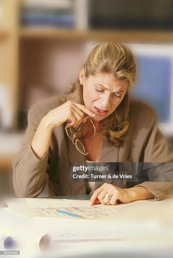 FROWNING BUSINESSWOMAN REVIEWING PLANS