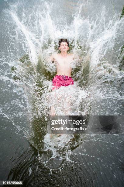 jonge man springt achteruit in een meer, water spatten rond - northern european descent stockfoto's en -beelden