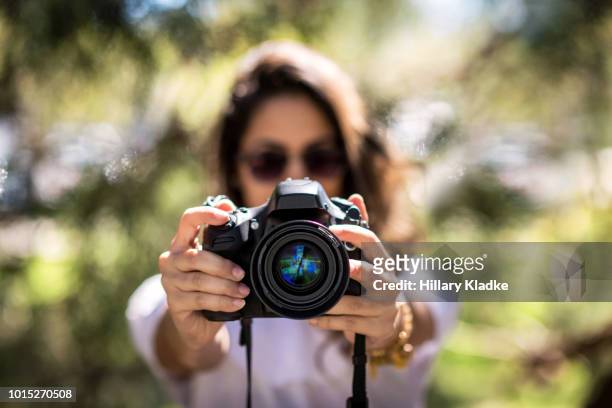 brunette holding camera - digitale spiegelreflexkamera stock-fotos und bilder
