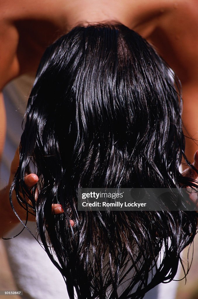 Woman running fingers through hair, rear view, close-up