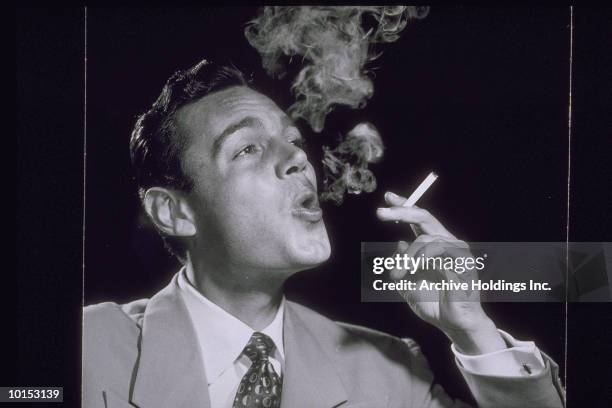 man smoking cigarette, exhaling, 1957 - smoking cigarette 1950s stock pictures, royalty-free photos & images