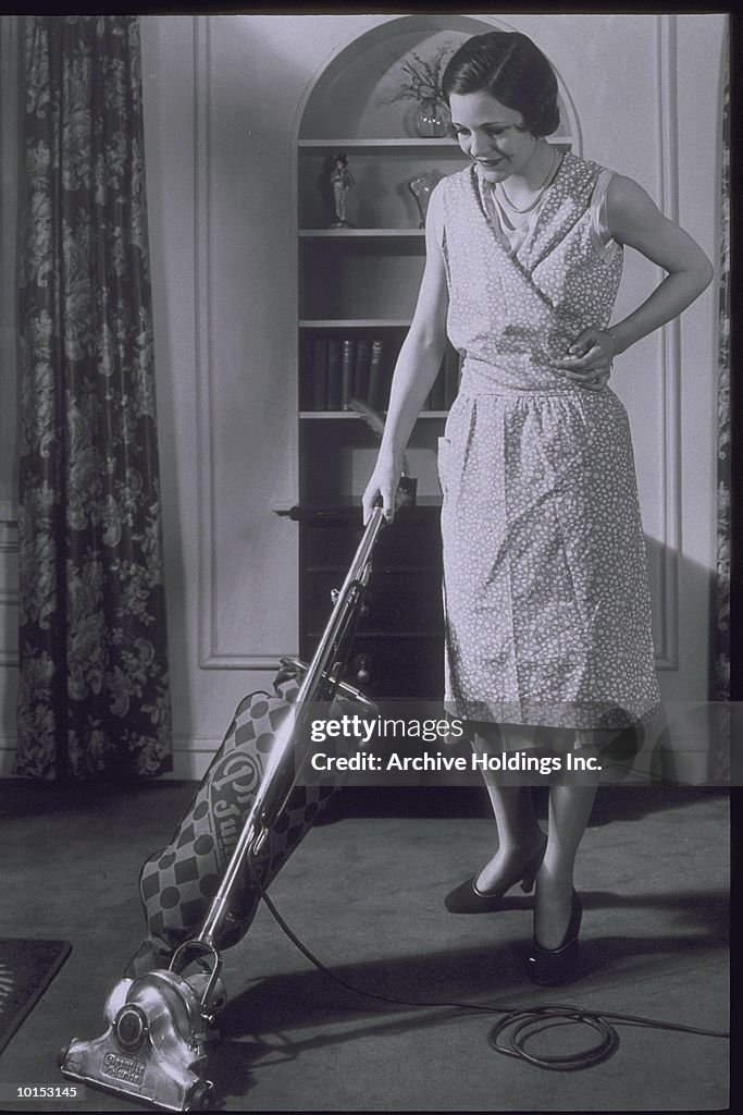 WOMAN VACUUMING LIVING ROOM, 1930S