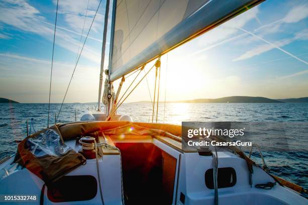 velero cruzando al atardecer - barco velero fotografías e imágenes de stock