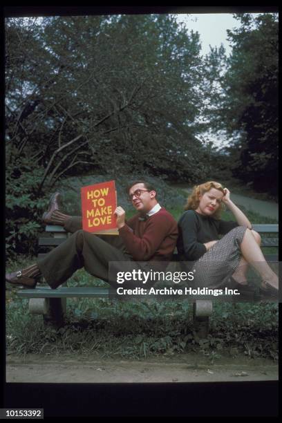 couple sitting on park bench, man reading book - bored girlfriend stock pictures, royalty-free photos & images