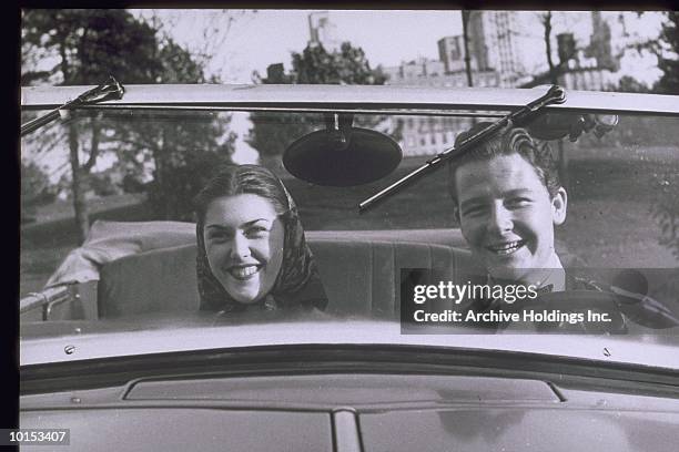 couple in front seat of convertible, circa 1950s - romance photos stockfoto's en -beelden