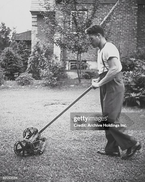 man mows lawn with manual lawn mower - cortacésped manual fotografías e imágenes de stock