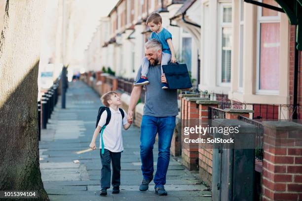 mid adult man walking down the street with his sons - british culture walking stock pictures, royalty-free photos & images