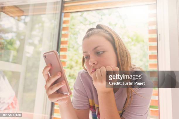 teenage girl using smartphone in bedroom - 14 year old blonde girl stock pictures, royalty-free photos & images