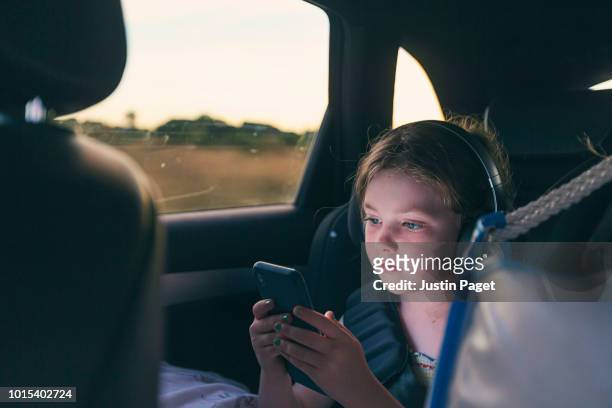 young girl using smartphone on roadtrip - rücksitz stock-fotos und bilder