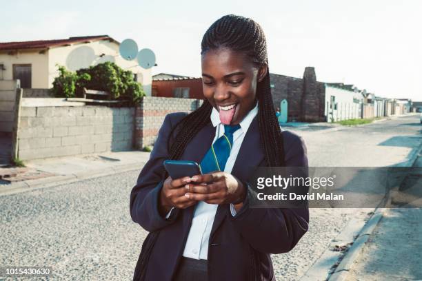 schoolgirl laughing as she looks at something on her mobile phone. - township - fotografias e filmes do acervo