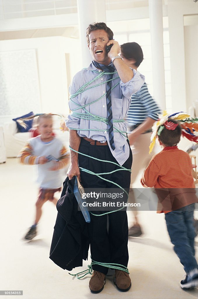 Children (4-7) tying up father with phone cord (blurred motion)