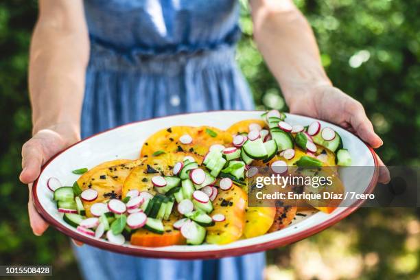 a summer platter of heirloom pineapple tomato salad 2 - 盛り付け 手 ストックフォトと画像