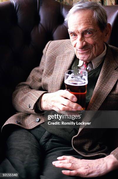mature man sitting in pub chair with beer - senior men beer stock pictures, royalty-free photos & images