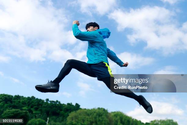 sporty young man jumping and running outdoors - running midair stock-fotos und bilder