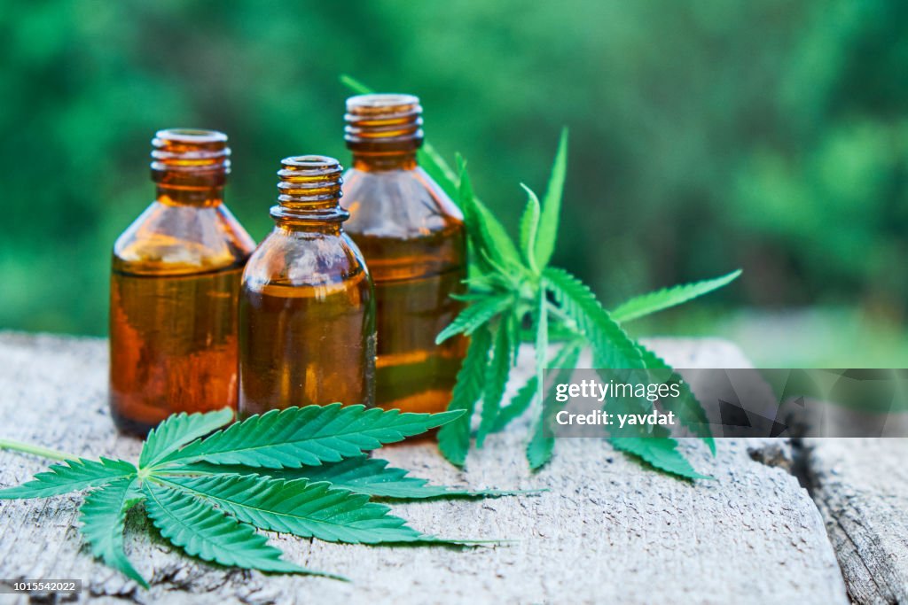 Hemp leaves on wooden background, seeds, cannabis oil extracts in jars