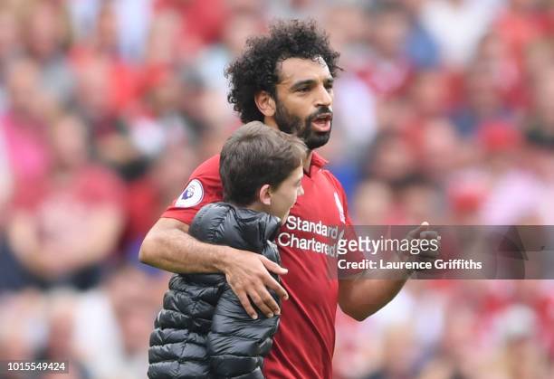 Fan runs onto the pitch and embraces Mohamed Salah of Liverpool during the Premier League match between Liverpool FC and West Ham United at Anfield...