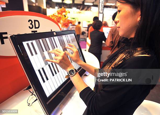 Woman plays music on a flat panel screen using multiple-touch technologies at a booth of the Taipei World Trade Centre, where Computex Taipei, Asia's...