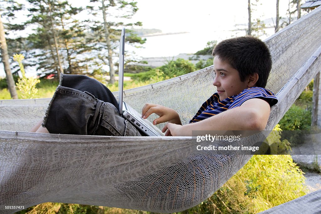 Boy in hammock using laptop computer