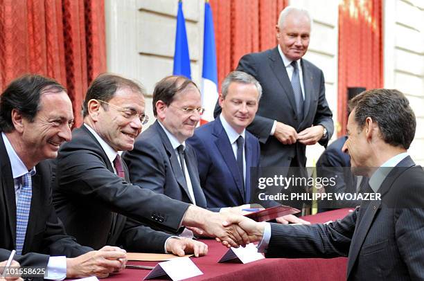 French President Nicolas Sarkozy shakes hands with Casino hypermarket group president Jean-Charles Naouri beside French Leclerc hypermarket chain...