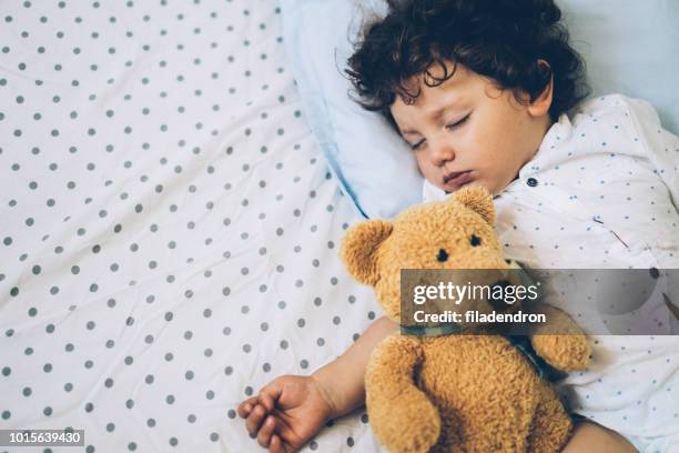 enfant en bas âge dormant avec ours en peluche - baby close up bed photos et images de collection