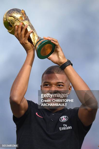 Paris Saint-Germain's French forward Kylian Mbappe poses and holds the 2018 World Cup Trophy prior to the French L1 football match between Paris...