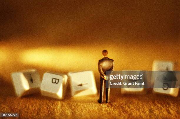 businessman standing before computer keys - businessman figurine stock pictures, royalty-free photos & images