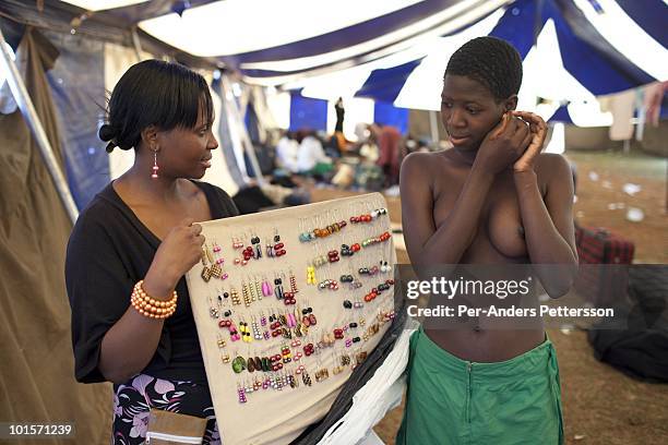 An unidentified girl buys earrings from a trader before a traditional Reed dance ceremony at the Royal Palace on August 29 in Ludzidzini, Swaziland....