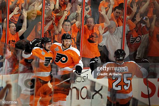 Matt Carle looks on as teammates Danny Briere and Claude Giroux of the Philadelphia Flyers celebrate after Briere scored a goal in the first period...