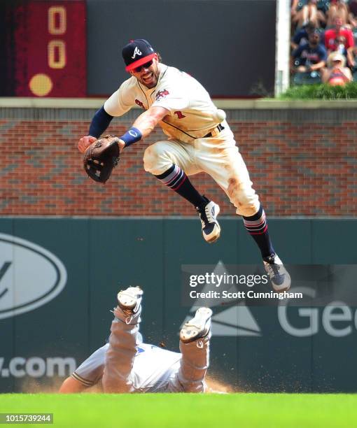 Dansby Swanson of the Atlanta Braves is unable to make the catch of an errant pickoff attempt as Erik Kratz of the Milwaukee Brewers dives back...