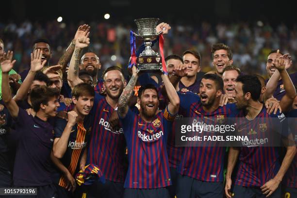 Barcelona's Argentinian forward Lionel Messi carries the cup as they celebrate at the end of the Spanish Super Cup final between Sevilla FC and FC...