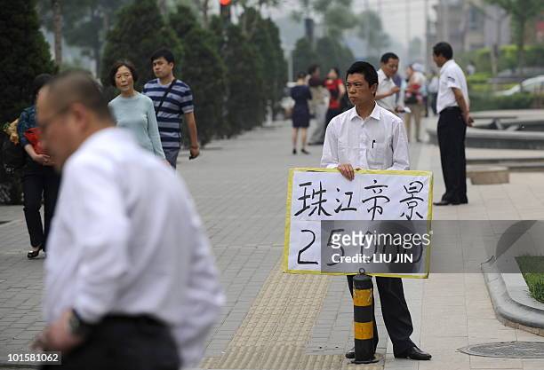 China-economy-property,FOCUS BY Fran Wang A real estate agent holds a placard showing the housing price along a street in Beijing on May 16, 2010....