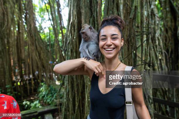 woman interacting with a monkey in bali, indonesia - ubud monkey forest stock pictures, royalty-free photos & images