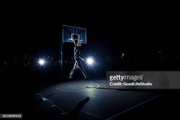 young man playing basketball at night - taking a shot sport stock pictures, royalty-free photos & images