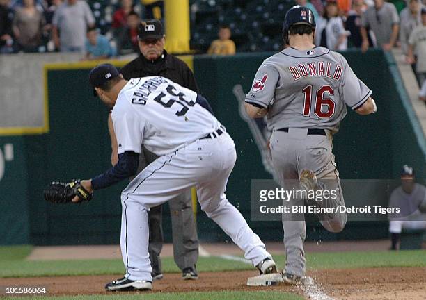 Pitcher Armando Galarraga of the Detroit Tigers covers first base as Jason Donald of the Cleveland Indians steps on the bag while umpire Jim Joyce...