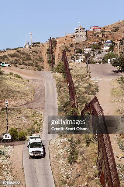 Border Patrol agent drives along a fence which separates the cities of Nogales, Arizona and Nogales, Sonora Mexico, a frequent crossing point for...
