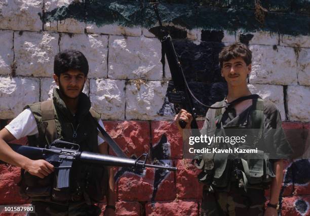 Amal militia men armed with M16 automatic assault rifles stand in front of Lebanon flag painted on a wall, during the civil war, 10th June 1986.