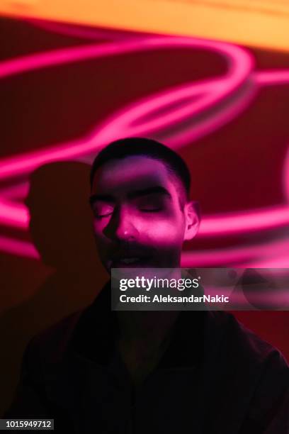 young man illuminated by neon lights - man face shadows stock pictures, royalty-free photos & images