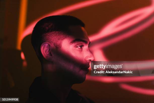 young man illuminated by neon lights - man face shadows stock pictures, royalty-free photos & images