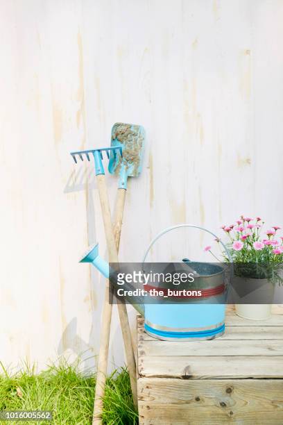 still life of spade and watering can in front of wooden wall in garden - tool shed wall spaces stockfoto's en -beelden