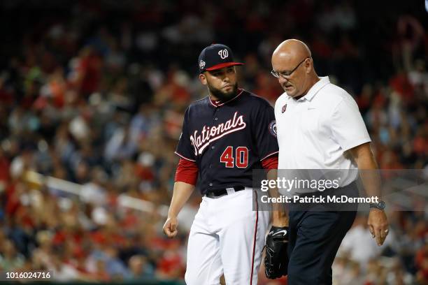 Kelvin Herrera of the Washington Nationals walks off the field with athletic trainer Paul Lessard after leaving the game with an apparent injury in...