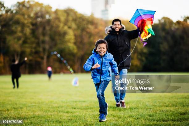 single dad helping son fly kite - kite toy stock pictures, royalty-free photos & images
