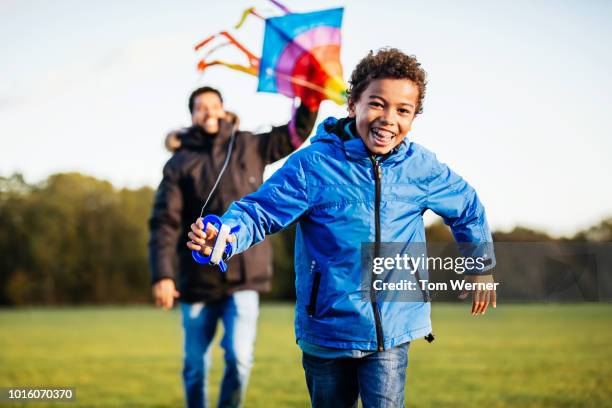 young boy running with kite in the park - flying dad son stock pictures, royalty-free photos & images