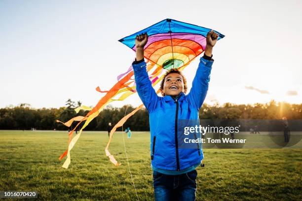 young boy enjoying learning how to fly kite - abrigo azul fotografías e imágenes de stock