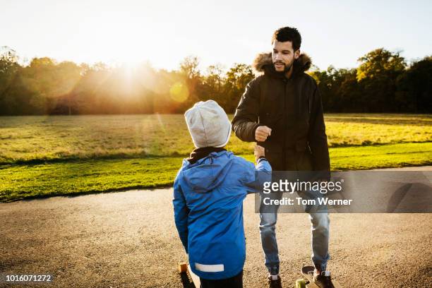 single dad giving his son a fist bump - father longboard stock pictures, royalty-free photos & images