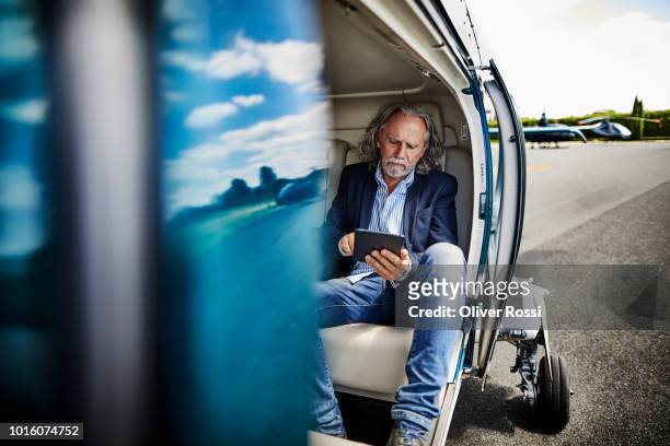 senior businessman using digital tablet in helicopter on airfield - big tech foto e immagini stock