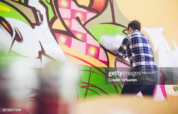 man painting graffiti on orange wall - graffiti artists stock pictures, royalty-free photos & images