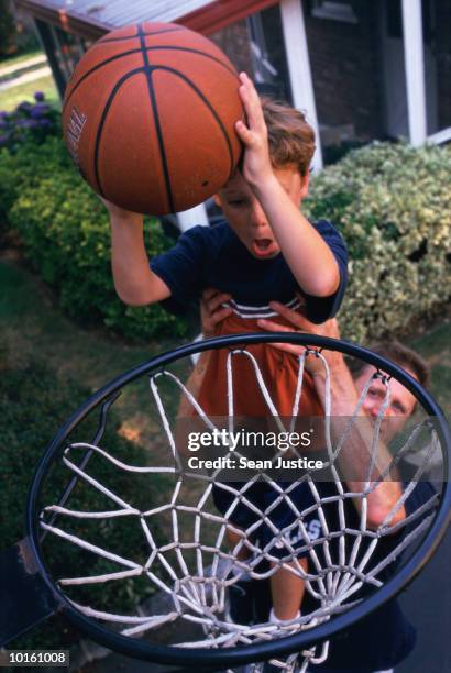 dad lifting son to dunk basketball - shooting baskets in driveway stock pictures, royalty-free photos & images