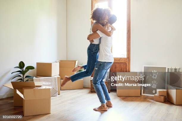 young man lifting woman in new house - young couple moving house stock pictures, royalty-free photos & images