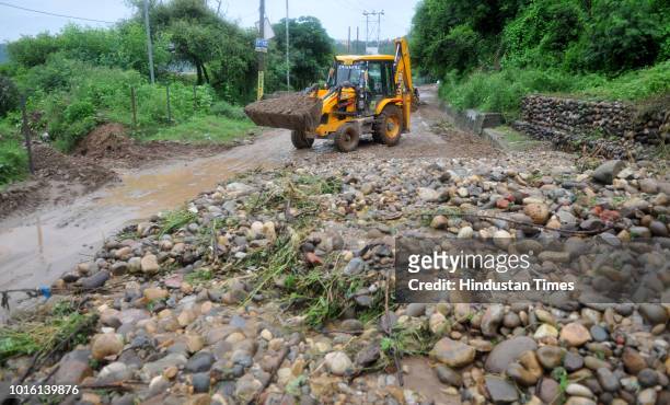 Driver on an excavator removes debris from a road Bypass road after heavy monsoon showers triggered a landslide on August 13, 2018 in Jammu, India.
